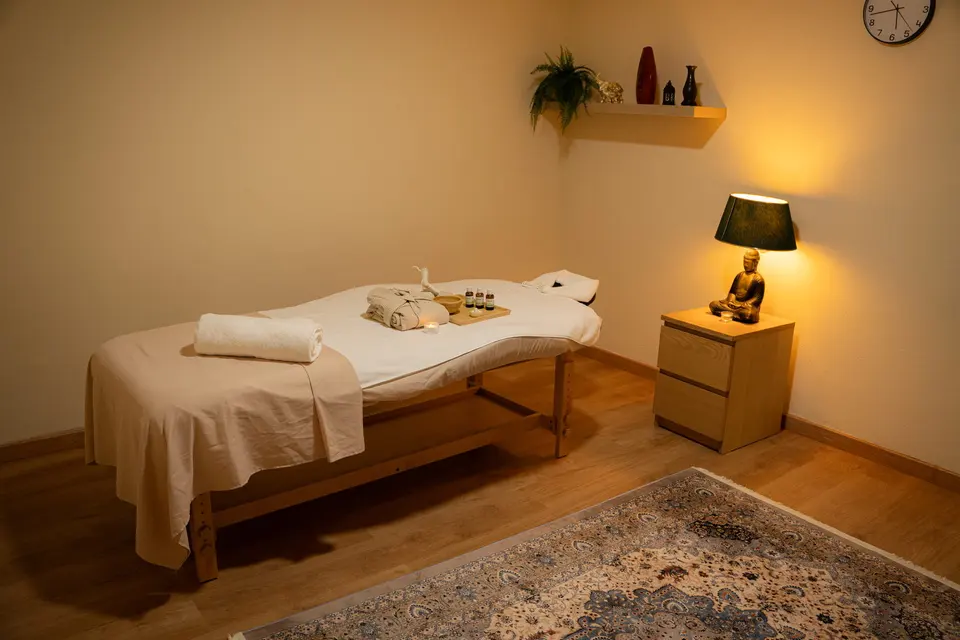 Sala de massagem preparada, com luz quente e toalhas limpas
